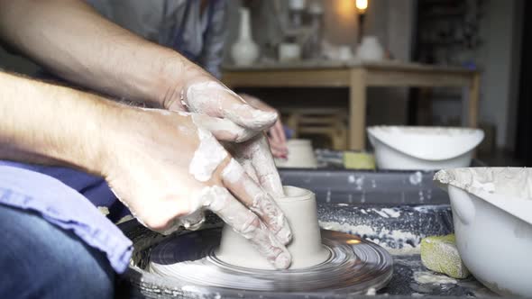 Man Holds Hands on Clay on Pottery Wheel