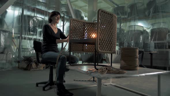 Furniture factory worker wraps a rope around an aluminum frame to create a beautiful modern chair.