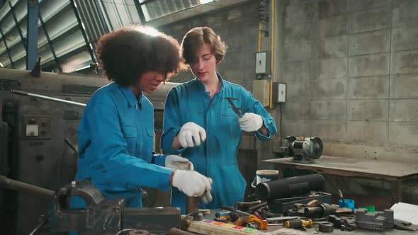 Two professional female workers work in the metalwork manufacturing factory.