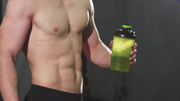Cropped Shot of a Shirtless Man with Perfect Abs Holding Water Showing Thumbs Up alt
