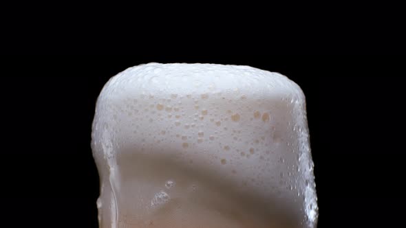 Lager Beer with Bubbles and Froth in Glass Over Black Background