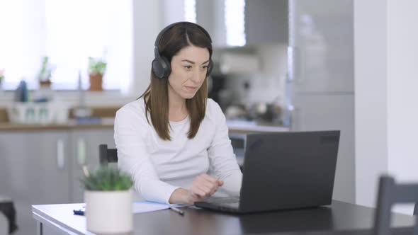 Woman with headphones making video call from home