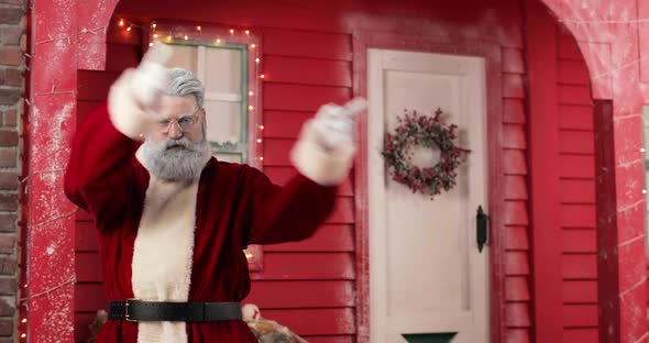 Modern Santa Claus is Funny Dancing on the Background a Red House with Lights in a Beautiful New