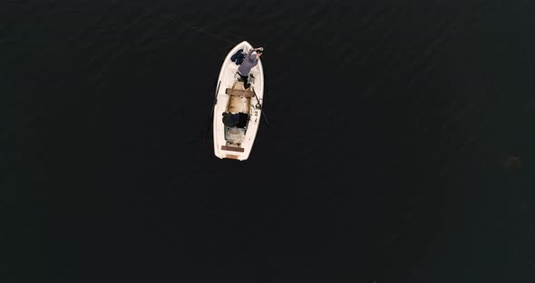 Aerial view of small white little sail boat cruise in dark ocean open water with two couple of frien alt