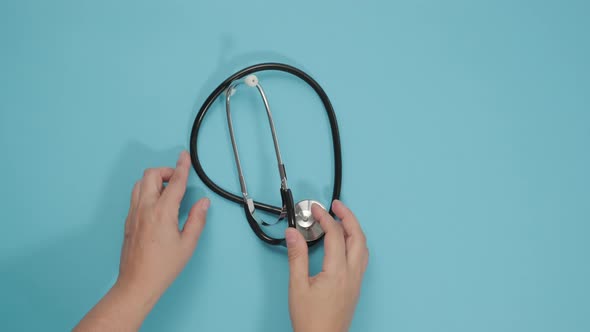 female hand puts on blue background a medical stethoscope alt