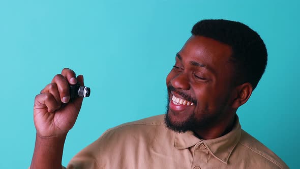 Mini Camera in Hand of African American Man in Blue Studio alt