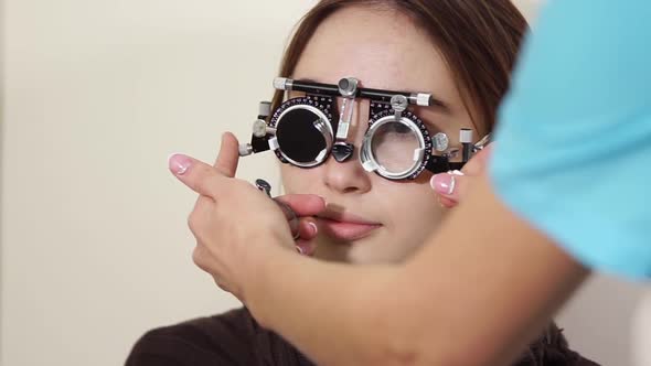 Ophthalmologist Is Trying on Lenses in a Trial Frame on Face of Woman alt