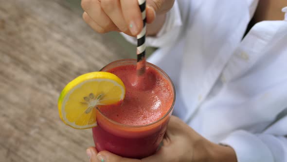 Top View of Female Swirling Her Berry Smoothie with Sustainable Paper Straw and Takes Drinks It alt