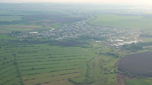 Aerial View on Green Fields Forest and River in Mist From the Plane Window alt