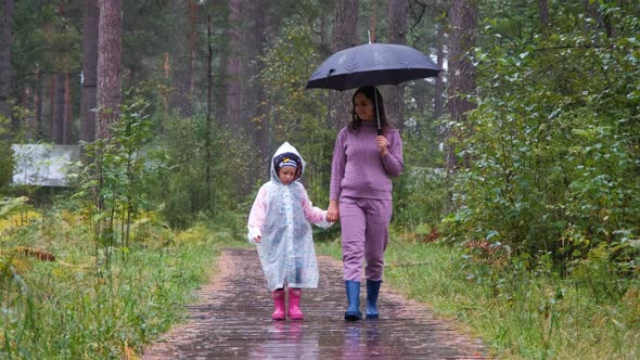 Mother with Daughter Walking in Autumn Rainy Day alt
