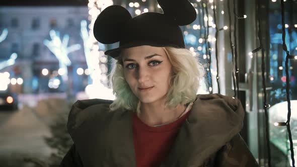 Cinematic Portrait of Young Funky Woman Outdoor in Wintertime at Night Having Fun Looking at Camera alt