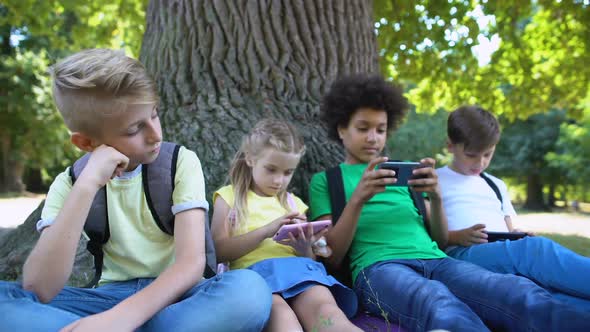 Boy Feeling Bored While Friends Playing Games on Phones Instead of Communication