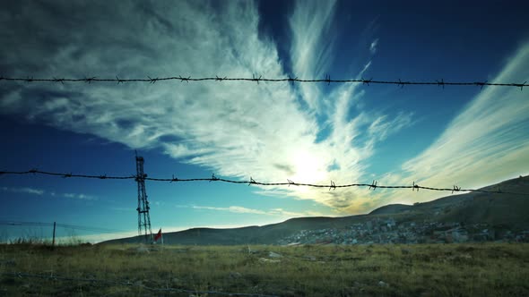 4K Motion time lapse from behind the wire mesh. Moving white clouds.