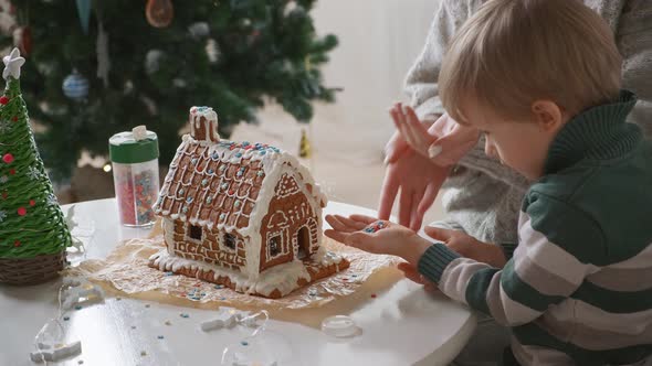 Little Boy with Mother Decorating Christmas Gingerbread House Together Family Activities and alt