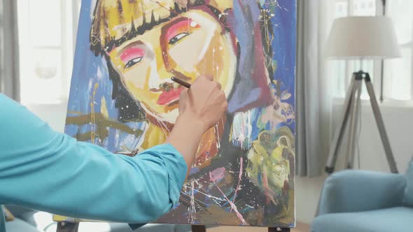 Asian Artist Man Holding Paintbrush Mixed Colour And Painting A Girl's Face On The Canvas alt