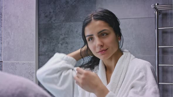 Mixed Race Woman Brushing Her Hair in Bathroom Wearing Bathrobe Looking at Mirror in Slow Motion alt