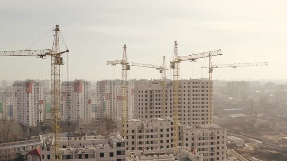 Shot in Height of Several Yellow Construction Cranes and Construction of New Buildings for Housing alt