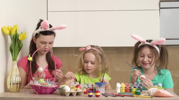 Cute Girls Paint Easter Eggs in Bunny Ears with Paint