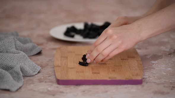 Female hands cutting the soft prunes into equal strips.	