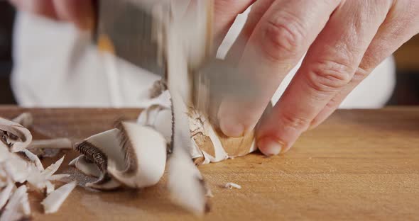 Close up of a chef knife slicing a portobello mushroom alt
