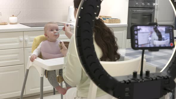 Recording Video with Mobile Phone and Ring Light of Mother Feeding Her Oneyearold Baby Boy with alt
