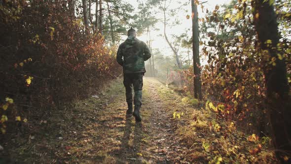 Time Lapse Interval of Soldier Walk in Forest at Sunset with Rifle on Shoulder alt