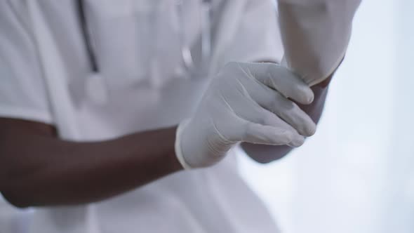 Closeup Male African American Hands Putting on Surgical Gloves alt