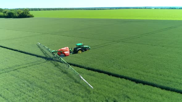 The Protection Of Plants.Tractor Spraying A Green Wheat Field alt