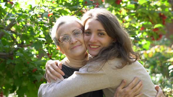 Happy Senior Mother in Eyeglasses is Hugging Her Adult Daughter the Women are Enjoying Together alt