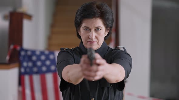 Serious Caucasian Policewoman Looking at Camera Raising Hands with Armed Gun alt