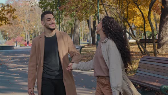 Young Active Hispanic Couple Walking Holding Hands Hugging in Autumn City Park Beautiful Girl alt