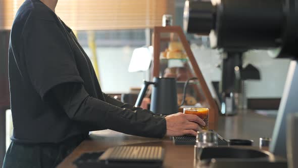 4K Asian woman barista making iced black coffee with orange juice serving to customer alt