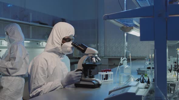 Male Scientist Using Microscope and Looking at Camera alt
