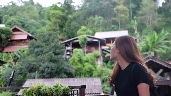 Slow motion of a woman sitting and looking around a greenery rural village