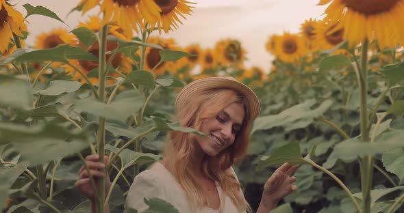 Nice Girl Beckons with Her Finger and Runs Away in a Field of Sunflowers
