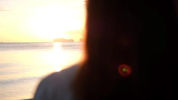 Rear view of a woman watching  sunset on the beach