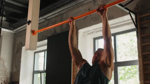 Young Man Exercising on Horizontal Bar in Gym alt
