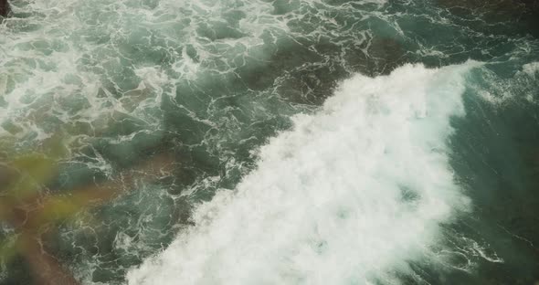 Close Up Slow Motion View of the Wave Moving on the Water and Crashing Ashore the Rocky Tropical alt