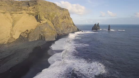 Aerial view of black beach with big waves and cliffs in Vik, Iceland