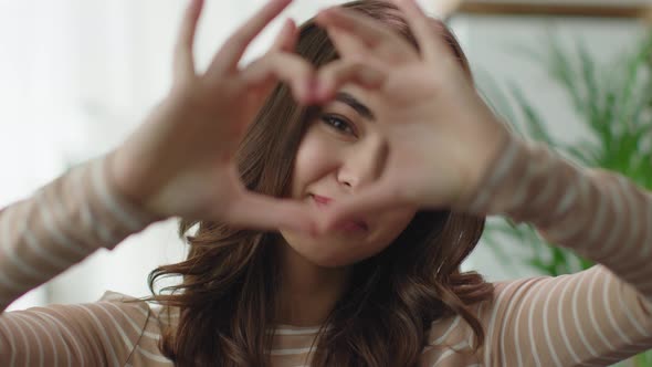 Smiling Young Woman Volunteer Showing Hands Sign Heart Shape Looking at Camera