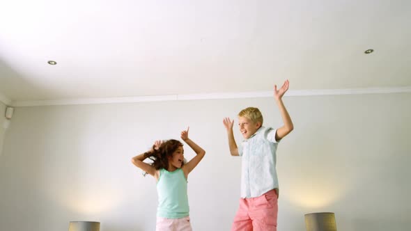 Siblings having fun on bed in bedroom alt