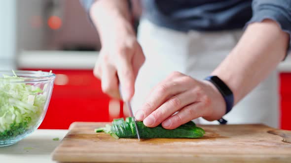 Male Hands with Knife Cuts Fresh Cucumber for Green Salad alt
