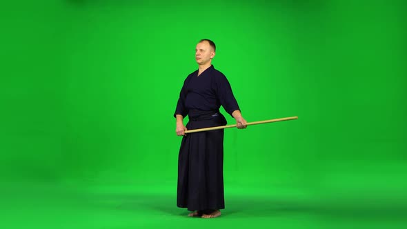 Masculine Kendo Warrior Practicing Martial Art with the Bamboo Bokken on Green Screen. alt