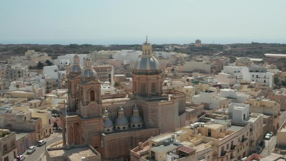 Beautiful Blue and Brown Church Towers in Small Mediterranean Town on Malta Island, Aerial Slide alt