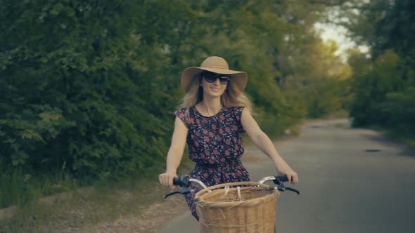 Woman Cyclist Riding On Bicycle In City Park. Woman In Hat Enjoying Summer. Bike On Countryside. alt