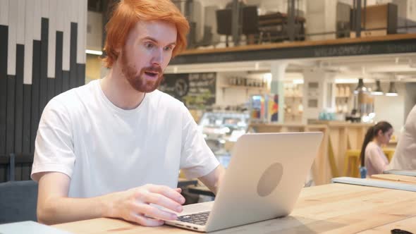 Excited Redhead Beard Man Celebrating Success Sitting in Cafe alt