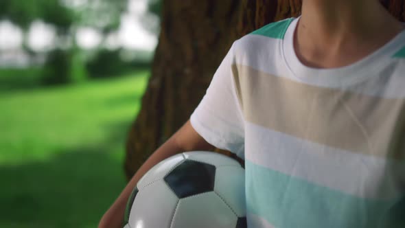 Portrait of Boy Holding Ball Near Tree alt