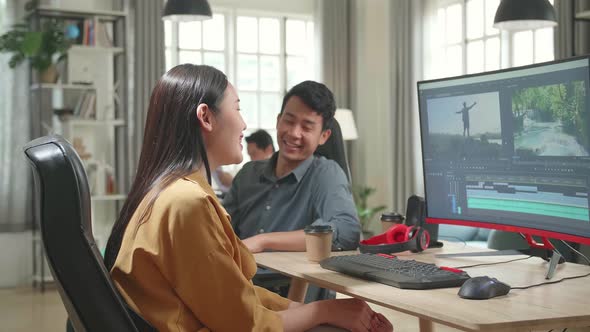 Happy Asian Female Video And Sound Editor Works With Her Male Colleague On Personal Computer alt