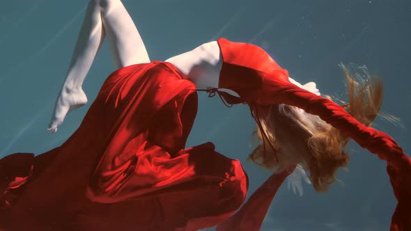 Attractive Redhaired Young Woman Swims Beautifully Underwater in a Red Dress alt