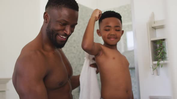 African american father and son flexing their muscles in mirror taking selfie together alt